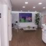 Recepção da clínica Bonapele Estética com sofá branco, poltronas roxas, mesa de centro e decoração elegante, transmitindo acolhimento e modernidade.