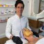 Biomédico Dr. Sidney Ruggero ao lado de paciente durante tratamento de limpeza de pele com máscara dourada em clínica de estética.